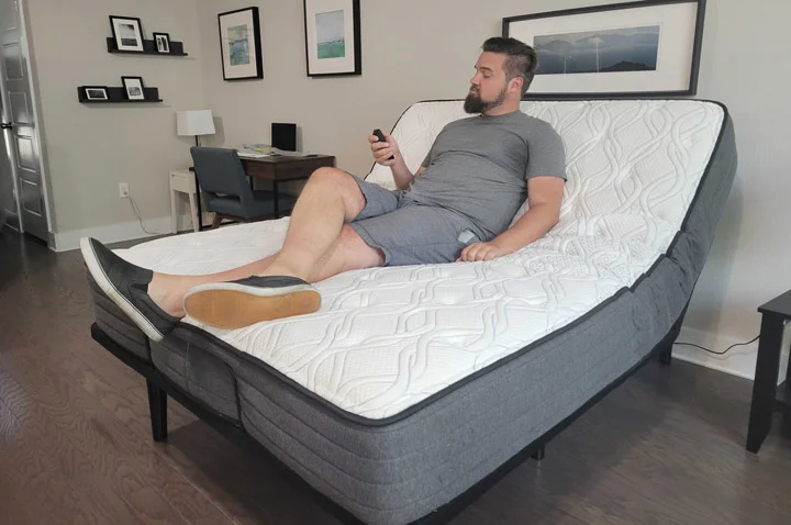 A man rests on the Sealy Ease while adjusting it