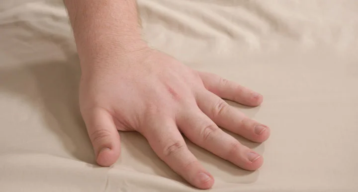 A hand brushes over the Brooklyn Bedding Deep Pocket Bamboo Cotton sheets.